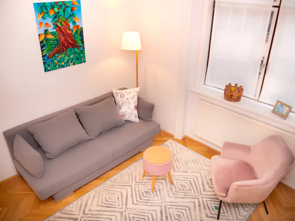The counselling room with sofa, reading lamp and a painted tree on the wall